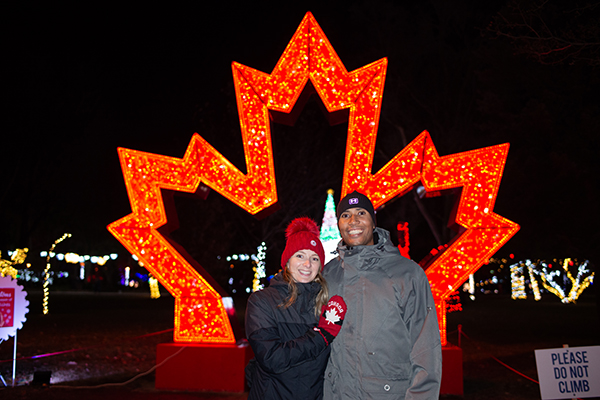 Couple posing in front of illuminated maple leaf