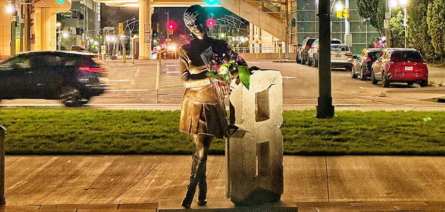 Rosalie Trombley and Big 8 sculpture with bouquet of flowers at night with Caesars Windsor in background