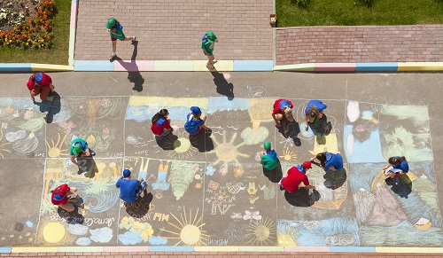 Overhead view of kids and adults making sidewalk chalk art