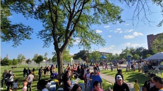 Residents gathered outside in a park at a Downtown Windsor Community Collaborative potluck event at Wigle Park