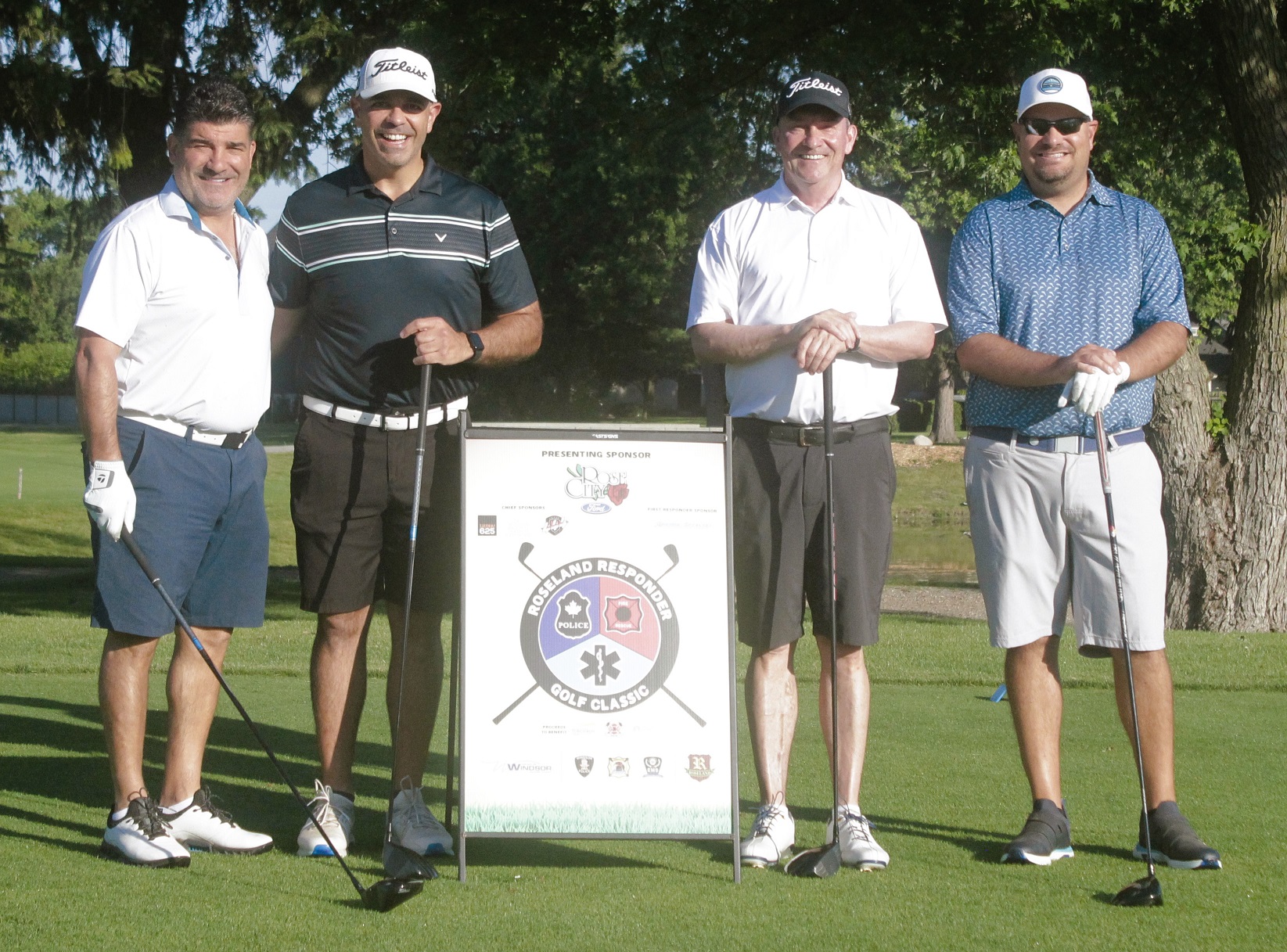 Four  men with golf clubs standing together with a Roseland Responder Golf Classic sign