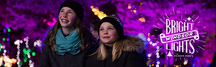 Two girls bundled up for chilly weather and looking up with delight at Bright Lights Windsor