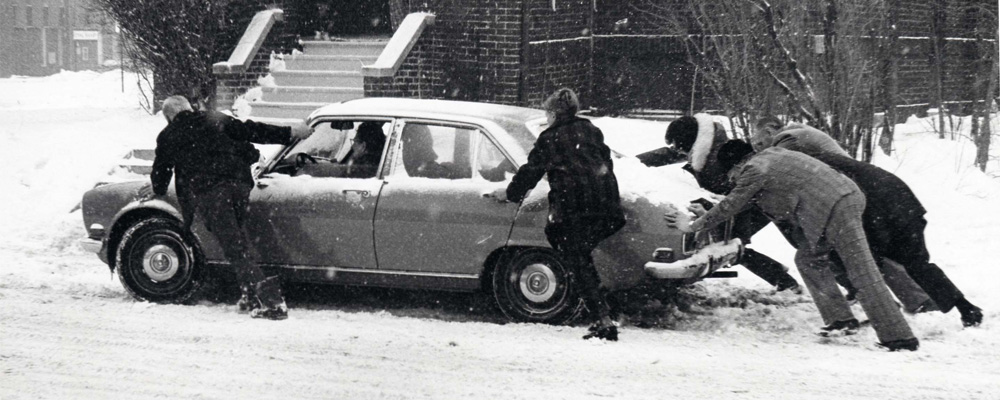 People pushing a car stuck in the snow. 