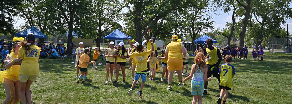 Team of kids celebrating and being congratulated by the supervisor team at an outdoor activity
