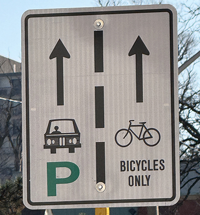 Road sign indicating cars and parking on the left, bicycles only on the right